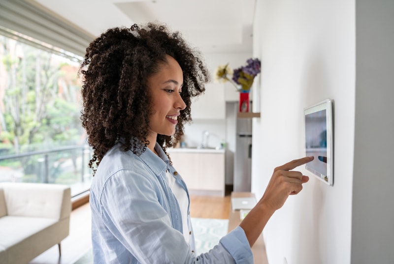 woman adjusting smart thermostat