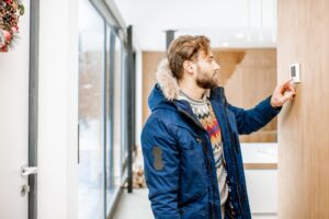 Cold Man Adjusting Thermostat